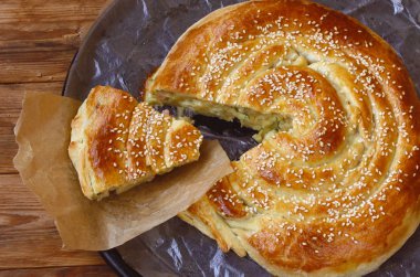 Ev yapımı pasta peynir, jambon ve baharatlı otlar ile serpilir ile susam ahşap bir masa, üstten görünüm üzerinde siyah bir tabak üzerinde