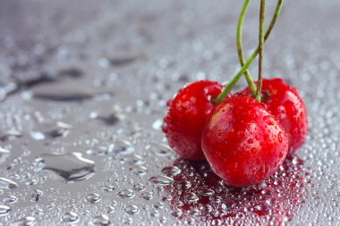 Üç olgun tatlı kiraz ayna yüzeyinde su damlaları içinde makro