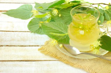 Cam bardak ıhlamur çayı, ıhlamur ile beyaz tahta masaya çiçek dalları