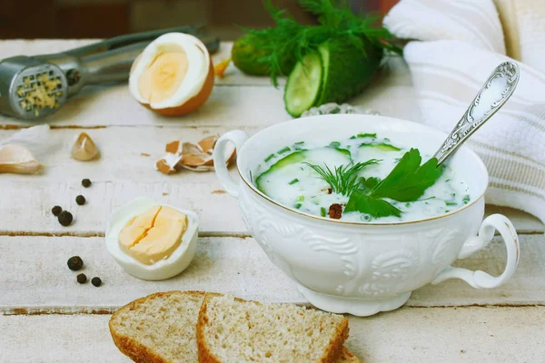 soğuk yoğurt çorbası salatalık, otlar, haşlanmış yumurta ve ahşap masa, closeup üzerinde beyaz kapta sarımsak ile