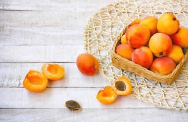 olgun tatlı kayısı sepeti dekoratif peçeteye Beyaz ahşap masa üzerinde