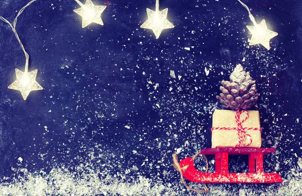 Weihnachten Roter Schlitten Tragen Geschenkschachtel Tannenzapfen Lichterkranz Auf Schwarzer Oberfläche — Stockfoto