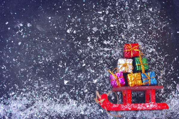 Natale Rosso Slitta Trasportare Mazzo Scatola Regalo Colorato Sulla Superficie — Foto Stock