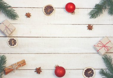 Noel antika arka plan, köknar ağacı dalları, hediye kutusu, kırmızı topları, tarçın, anason, Kuru turuncu, beyaz tahta masada üstten görünüm