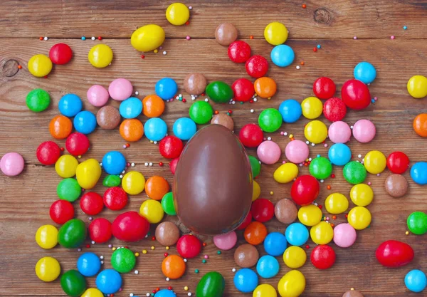 Easter chocolate egg, colorful candy on wooden table top view