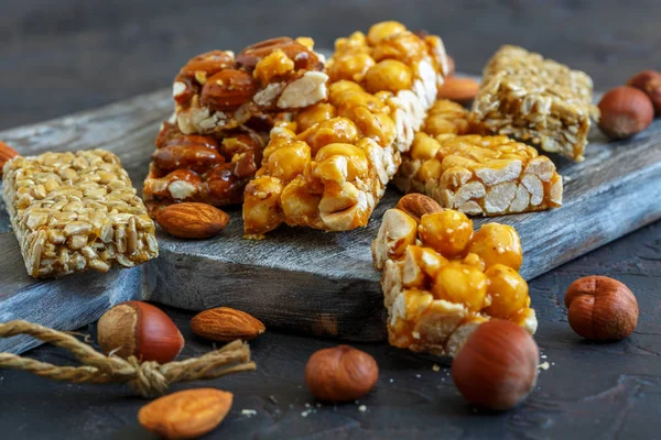 Artisanal bars with honey, almonds, hazelnuts, peanuts and sunflower seeds on a wooden serving board.