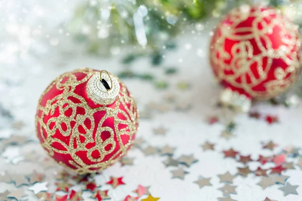 Christmas red balls on the background of shiny confetti and gold tinsel, selective focus.