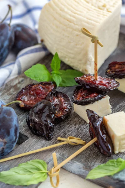 Dried plum with spices and homemade cheese on wooden serving board, selective focus.