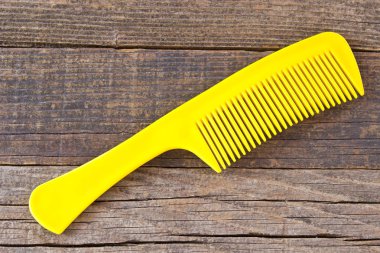 Ahşap zemin üzerine sarı plastik tarak