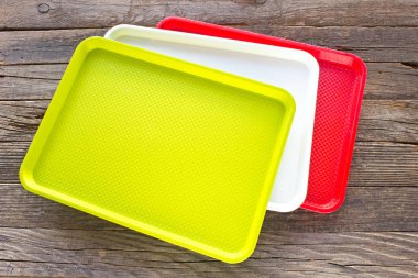 Ahşap arka plan üzerinde renkli öğle yemeği plastik kare gıda plakaları