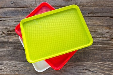 Ahşap arka plan üzerinde renkli öğle yemeği plastik kare gıda plakaları