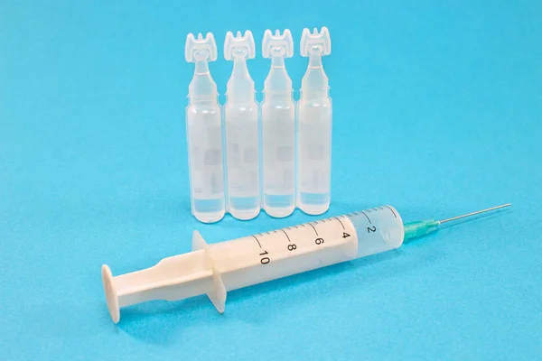 Ampule medyczne ze strzykawką izolowane na niebieskim tle — Zdjęcie stockowe
