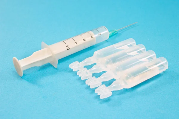 青い背景に隔離された注射器を持つアンプル医療 — ストック写真