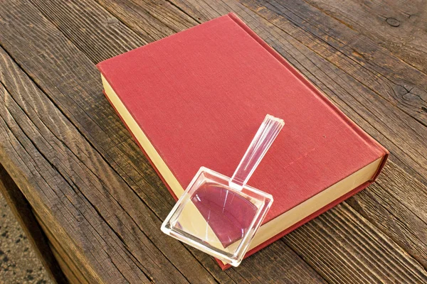 Magnifying glass with book on wooden table — Stock Photo, Image