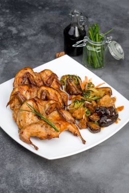 Beyaz kare bir tabakta kızarmış bıldırcın.