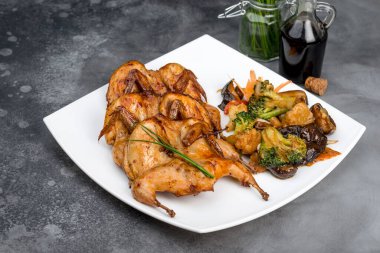 Beyaz kare bir tabakta bıldırcın kızartması. Yakın çekim.