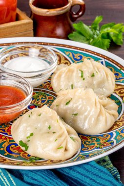 Buharda pişirilmiş mantalar sos ve ekşi kremayla servis edilir. Yakın çekim.