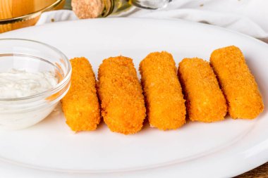 Soslu beyaz tabakta peynir çubukları. Yakın çekim.