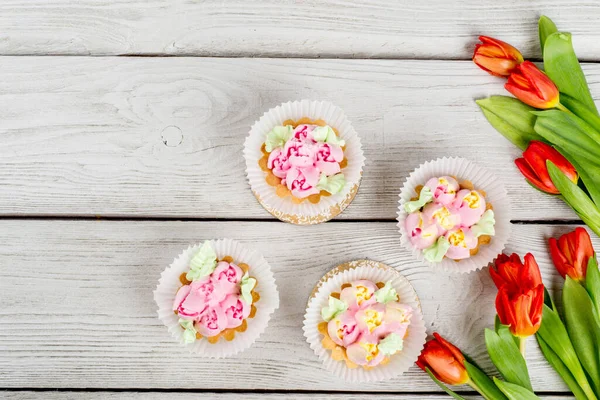 Flowers tulips dessert cake shot on white wooden background close-up