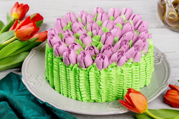 Flowers tulips dessert cake shot on white wooden background close-up