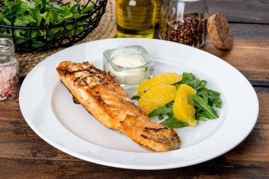 Beyaz bir tabakta, soslu ve limonlu bir parça kızarmış balık. Dekorasyonda çekilmiş.