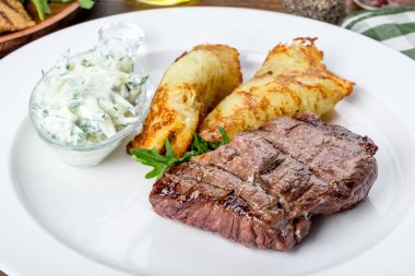 Beyaz tabakta, krep ve soslu biftek. Yakın çekim.