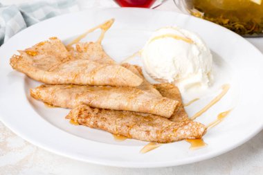 Beyaz tabakta kremalı dondurmalı krep var. Yakın çekim.