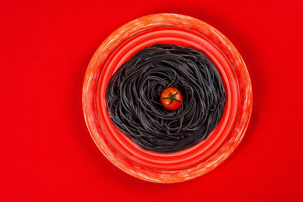 Fideos Negros Con Tomates Plato Rojo Sobre Fondo Rojo Tiro —  Fotos de Stock