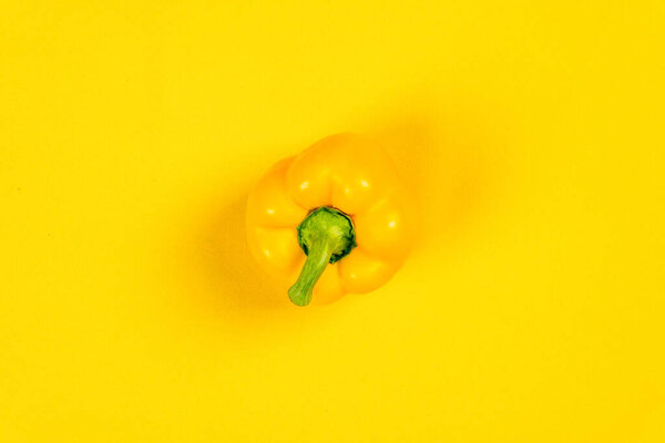 Yellow pepper photographed on a yellow background from above with shadows