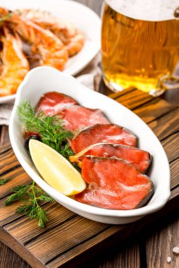 Aperatifli bira, ahşap arka planda kırmızı balık ve karides.
