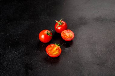 Siyah arkaplanda yakın plan çekimde vişne domatesleri.