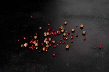 Siyah arkaplana dağılmış farklı türde biberler. Yakın çekim..