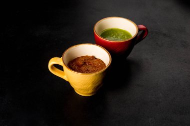 Adjika ve pesto sosu siyah arka planda renkli sos teknelerinde.