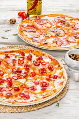 Beyaz ahşap arka planda iki pizza dikey olarak yakın çekim.