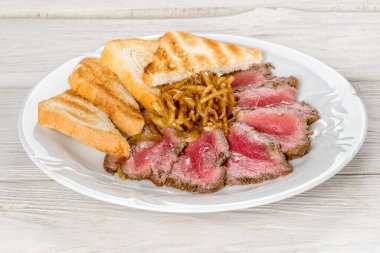 Beyaz tabakta kızarmış et ve tost. Ahşap beyaz arka planda yakın çekim..