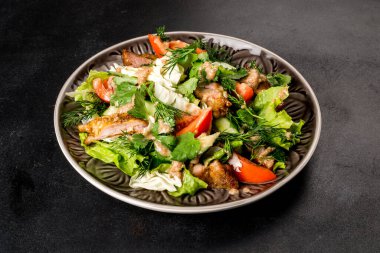 Siyah arka planda taze sebzeli ve otlu Gürcü salatası.