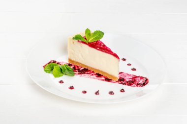 Nane yapraklarıyla süslenmiş reçelli bir parça peynirli kek.