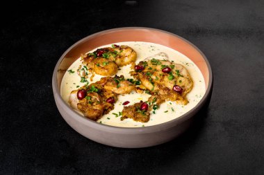 Siyah arka planda hafif bir tabakta chkmeruli servis ediliyor. Yakın çekim.