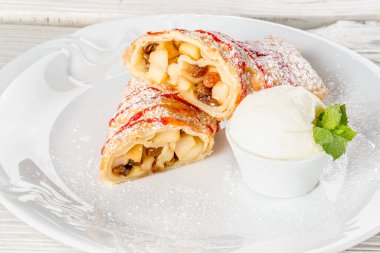 Nane şekeriyle süslenmiş beyaz bir tabakta elmalı turta.