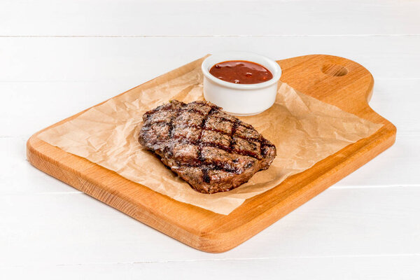 Close-up shot of beef steak on a wooden board with sauce