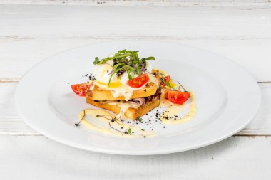 Beyaz bir tabakta taze otlarla dolu bir sandviçin yakın plan fotoğrafı.