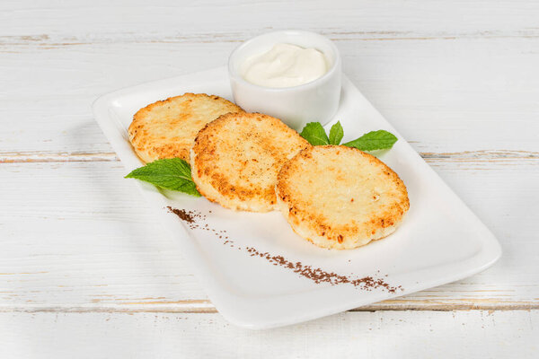 Чизкейки со сметаной, украшенные мятными листьями на белой тарелке
