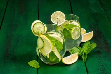 Limonlu detoks suyu, salatalık ve kırsal ahşap zemin üzerindeki nane rengi yeşil.