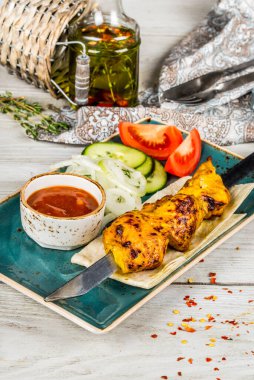 Kebap, soğan, pide, ahşap arka planda beyaz bir tabakta sos.