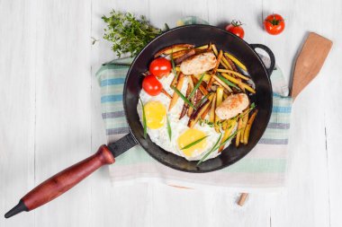 Kızarmış patates, et, yumurta, tavada domates.