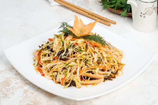 Chinese salad of fresh vegetables, noodles, cabbage in a white plate