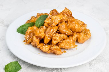 Yeşilliklerle süslenmiş beyaz, yuvarlak bir tabakta kızarmış meyveler. Yakın çekim.