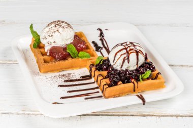 Beyaz, kare bir tabakta dondurma ve reçelli waffle. Yakın çekim.