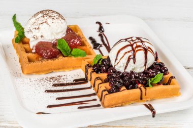 Beyaz, kare bir tabakta dondurma ve reçelli waffle. Yakın çekim.