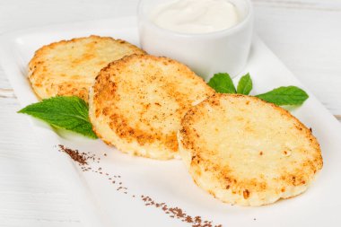 Beyaz tabakta süzme peynirli ve ekşi kremalı üç cheesecake. Yakın çekim.